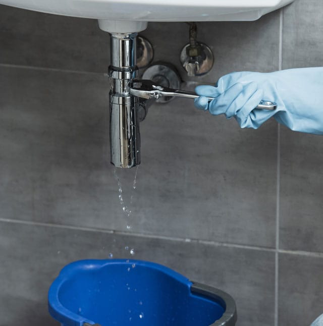 Partial view of woman in blue rubber glove using wrench